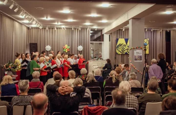grupa ludzi śpiewa przy akompaniamencie pianina, w tle widać publiczność