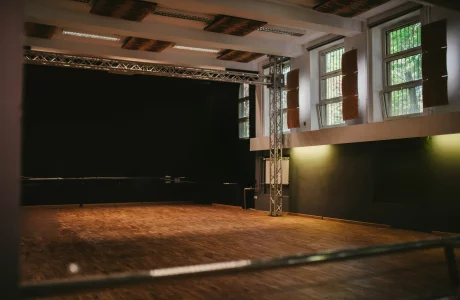 Zdjęcie sali widowiskowej Ośrodka Kultury Ochoty. Na pierwszym planie parkiet drewniany a na drugim scena koloru czarnego. Jest również czarne okotarowanie.