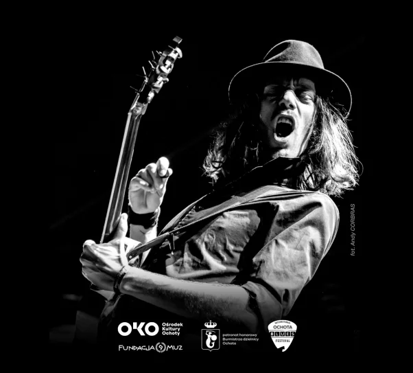 grafika przedstawia muzyka w kapeluszu z gitarą.