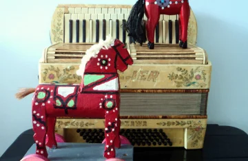 zdjęcie przedstawia akordeon i dwa drewniane koniki