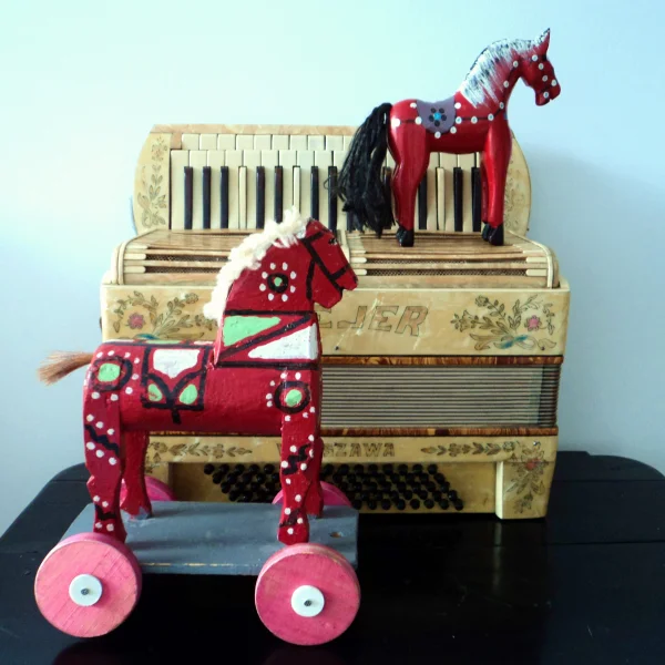 zdjęcie przedstawia akordeon i dwa drewniane koniki