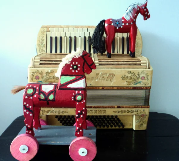 zdjęcie przedstawia akordeon i dwa drewniane koniki