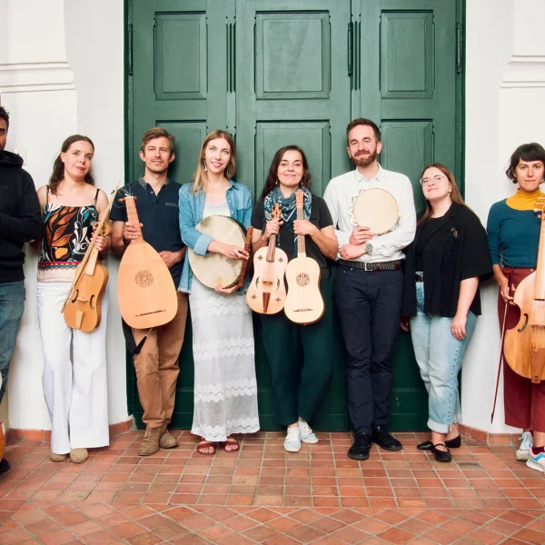 zdjęcie przedstawia 8 artystów stojących pod zielonymi drzwiami