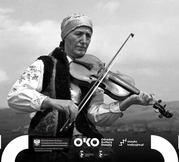 Starsza kobieta w tradycyjnym stroju ludowym siedzi na drewnianej ławce i gra na skrzypcach, w tle widać rozległy krajobraz wiejski.