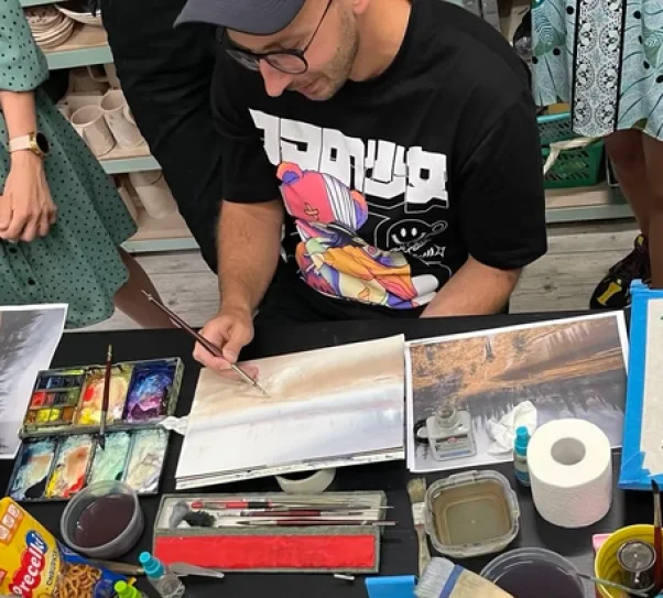 zdjęcie przedstawia artystę, który pokazuje kursantom jak stworzyć pracę