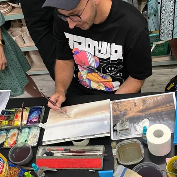 zdjęcie przedstawia artystę, kóry pokazuje kursantom jak stworzyć pracę