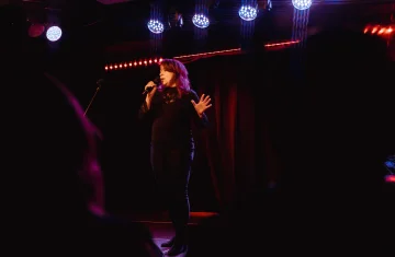 Zdjęcie przedstawia kobietę śpiewającą do mikrofonu