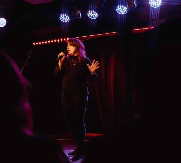 Zdjęcie przedstawia kobietę śpiewającą do mikrofonu