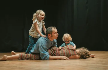 zdjęcie przedstawia rodzinę bawiącą się na podłodze. Dwoje dzieci oraz rodzice.